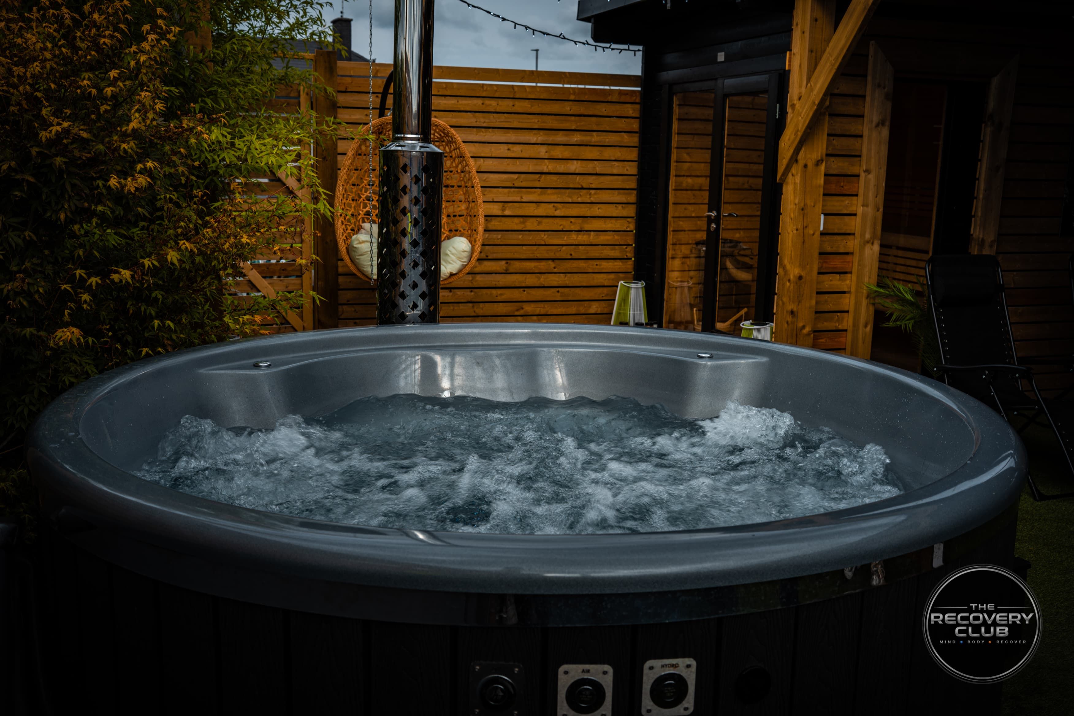 Bubbling water in the hot jacuzzi, with the garden chair behind it.